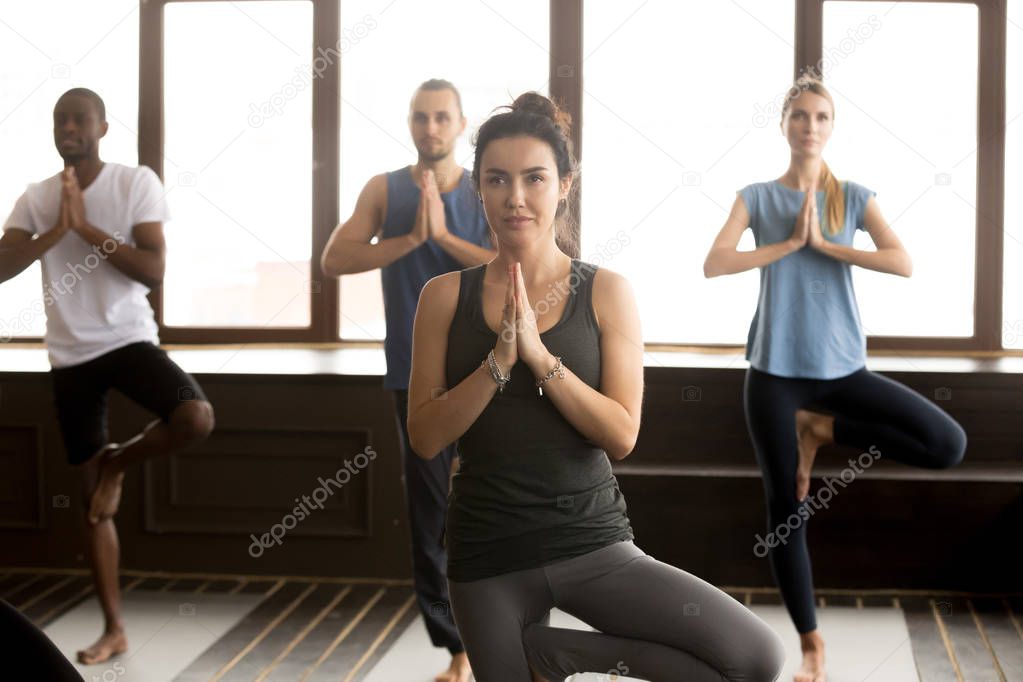 Group of sporty people in Vrksasana pose, close up