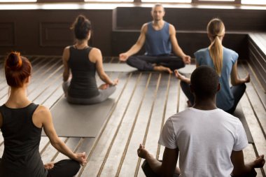 Sportif gençler Sukhasana alıştırmada oturma grubu