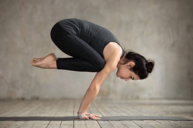 Genç kadının bakasana egzersiz yapması