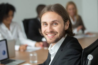 Toplantı, iş koç, farklı ortakları ile kameraya bakarak takım elbise çekici genç işadamı gülümseyen, başarılı takım lideri veya profesyonel icra müdürü baş vurdu portre