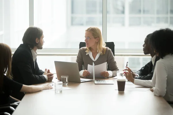 Woman boss discussing project at group meeting with diverse busi