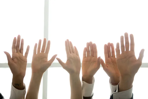 Multi-ethnic diverse people hands lifted up in the air, black and white palms raised as volunteering, initiative and engagement concept, business team training, activists get involved, close up view