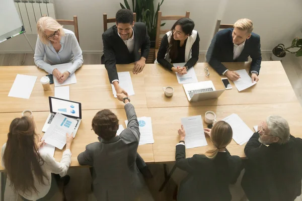 Multiracial businessmen shaking hands at diverse group meeting,