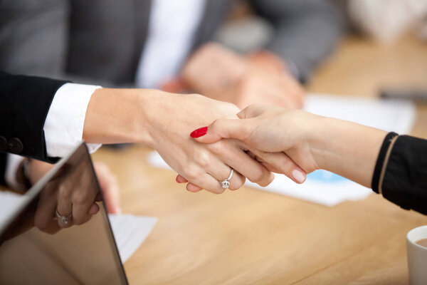 Businesswomen handshaking at group meeting, close up view of female hands shaking as concept of making deal, welcoming new partner, help, solidarity and support, women power in business concept