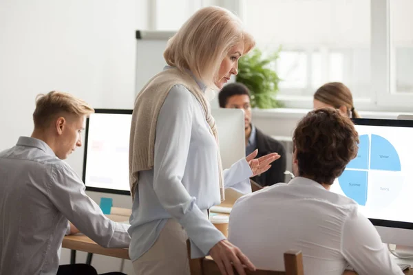 Senior mujer mentor ejecutiva supervisando el trabajo informático de ustedn — Foto de Stock