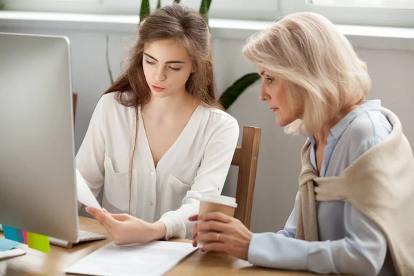 Unga och äldre affärskvinnor diskutera dokument arbetar toget — Stockfoto