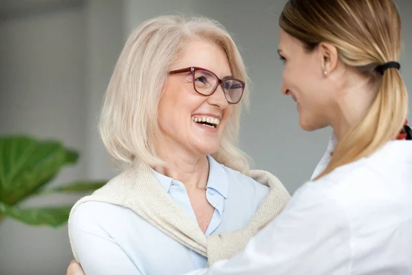 Bella felice donna anziana abbracciando giovane figlia adulta e la — Foto Stock