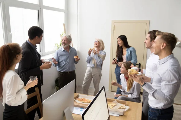 Дружеская команда бизнесменов разговаривает и смеется, поедая пиццу — стоковое фото