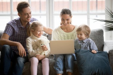 Eğleniyor çocuklu mutlu aile kanepede dizüstü bilgisayar kullanarak