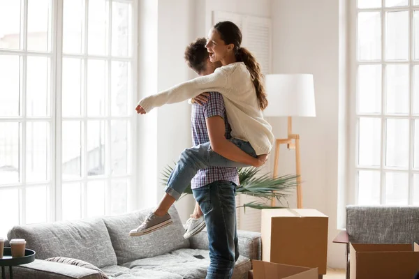 Excited couple celebrating moving day, man lifting embracing hap