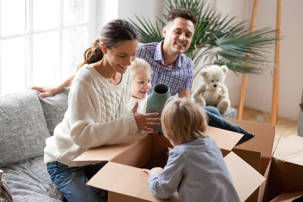Glückliche Familie mit Kindern beim Auspacken von Kisten beim Einzug ins neue Zuhause — Stockfoto