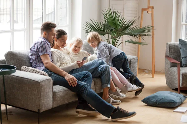 Famille heureuse avec enfants utilisant des applications mobiles ensemble sur le canapé — Photo