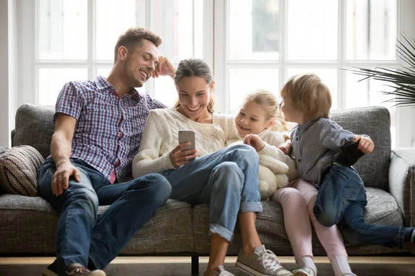 Famille joyeuse avec des enfants riant en regardant une vidéo drôle sur smart — Photo