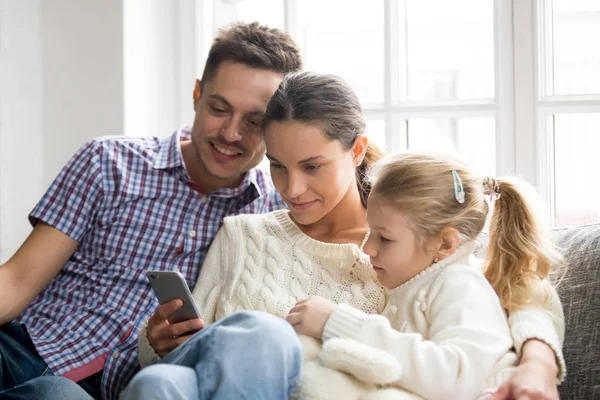 Genitori con figlia che guardano video sul cellulare a casa — Foto Stock