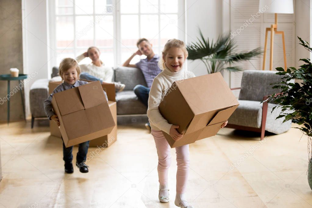 Excited kids playing holding boxes after moving in new home