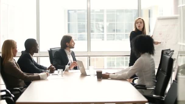 Ділова жінка дає презентацію багатоетнічним колегам під час зустрічі в залі засідань — стокове відео