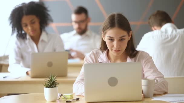 Mujer trabajando en el ordenador portátil, hablando con un colega africano en coworking — Vídeos de Stock