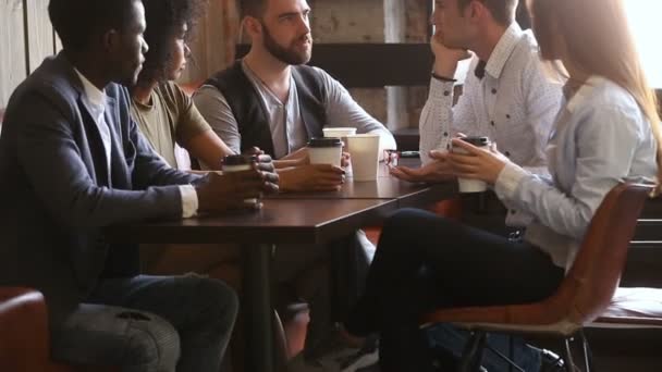 Международные молодые друзья весело пьют кофе за кофейным столиком — стоковое видео