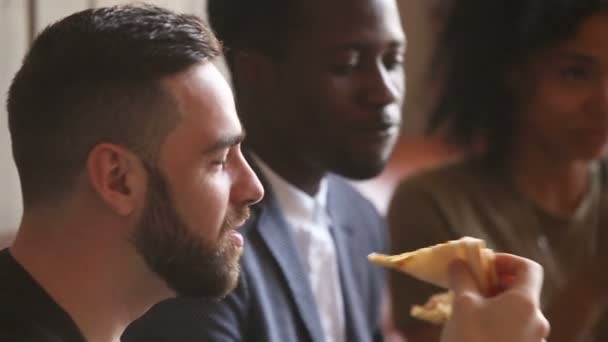 Multi-étnicos amigos blancos y negros comiendo pizza en la reunión en interiores — Vídeos de Stock