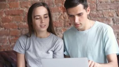 Genç casual çift online mağazasında ürünler seçme, dizüstü bilgisayar kullanarak