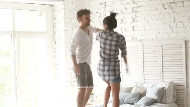 Jovem casal feliz dançando na cama, abraçando beijos no quarto — Vídeo de Stock