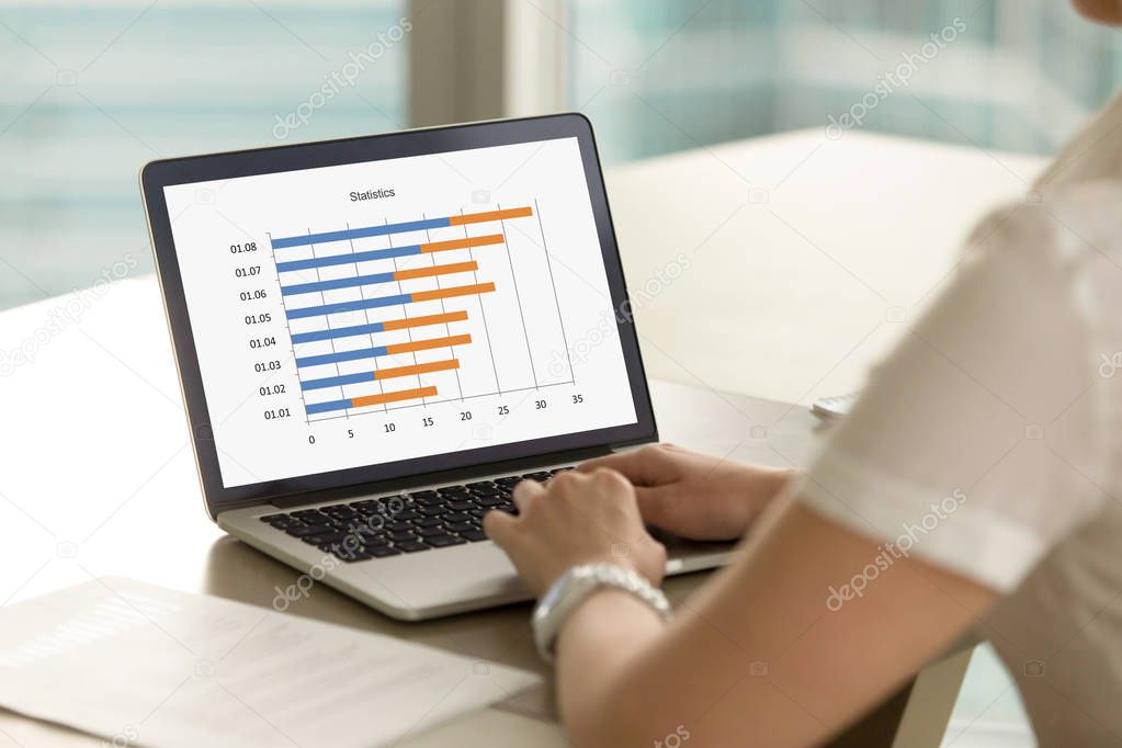 Business woman working on laptop with statistics graph on screen