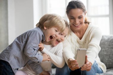 Smartphone cep telefonu ile iki sevimli çocuk ile anne alarak selfie gülümseyen