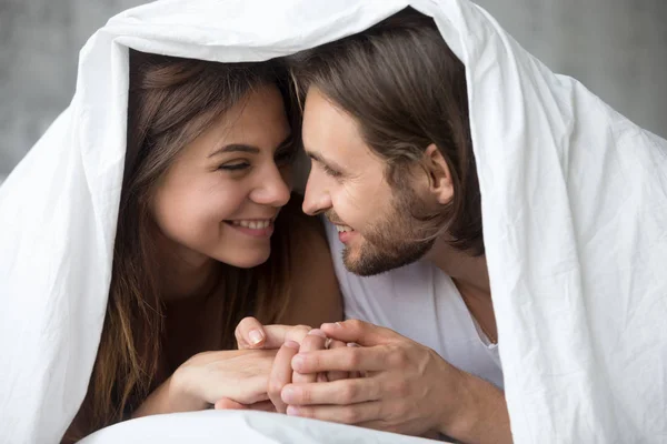 Young smiling couple in bed having fun covered with blanket — Stock Photo, Image