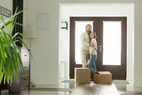 Переезд с концепцией коробок, счастливая пара обнимается в новом доме — стоковое фото