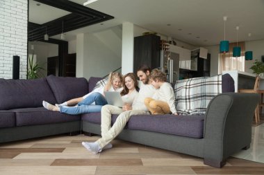 Ebeveynler çocuklarla oturma odasında dizüstü bilgisayar ile eğleniyor 