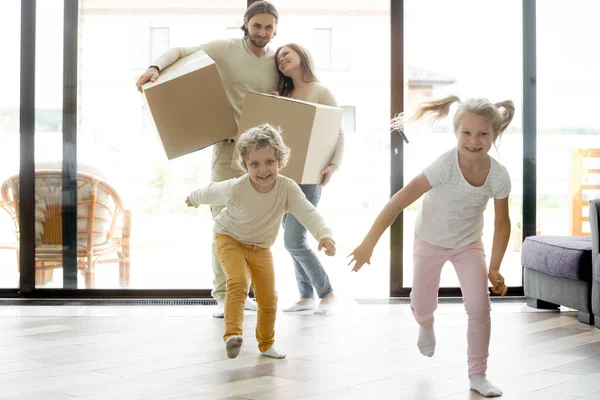 Divertidos niños felices corriendo en casa nueva en el día de mudanza —  Fotos de Stock