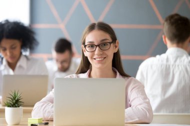 Gülümseyen kadın ortak çalışma masasında oturan kamera bakıyor