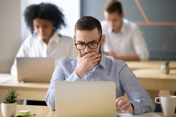 Focused businessman solving online problem working on laptop in 