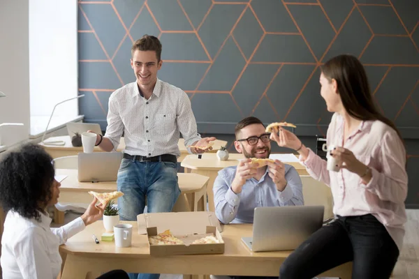 Vriendelijke divers team praten lachen eten pizza samen in — Stockfoto