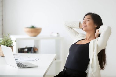 Relaxed happy asian woman enjoying break at workplace breathing  clipart