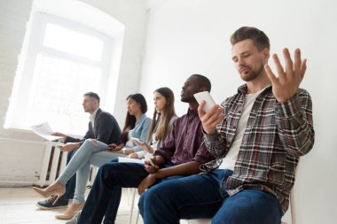 Kızgın adam insanlar sırada oturan telefon sorunu ile sinirli 