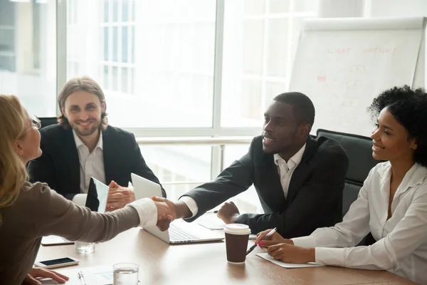 Empresario africano y mujer de negocios caucásica estrechando la mano en — Foto de Stock