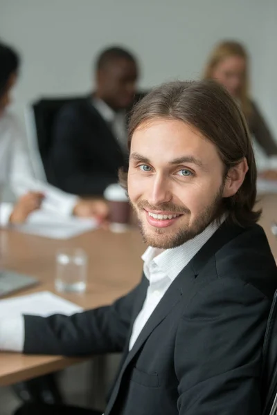 Sonriente joven hombre de negocios en traje mirando la cámara en la reunión — Foto de Stock