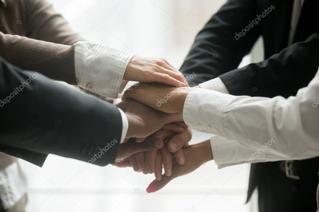 Diverse multiracial business team holding stacked pile of hands together promising help loyalty support, engaging in teambuilding, united at motivating training, coaching concept, close up view