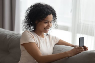 Gülümseyen siyah kadın cep telefonu kullanıyor ve selfie çekiyor.