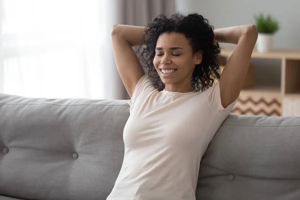 Smiling black woman relax on couch at home — ストック写真