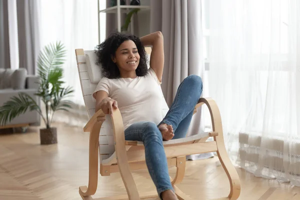 Mulher biracial feliz relaxar na cadeira de balanço em casa — Fotografia de Stock