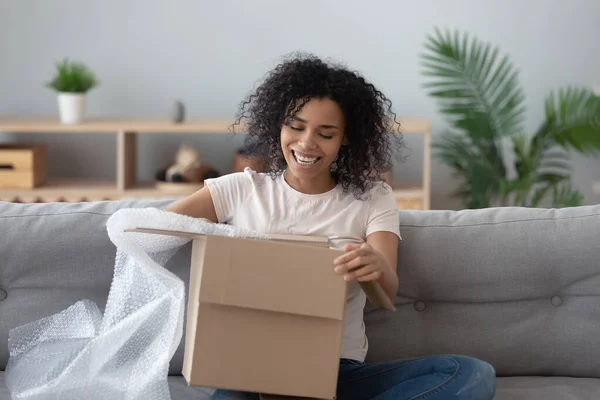 Smiling black girl unpack parcel at home shopping online — Stock Photo, Image