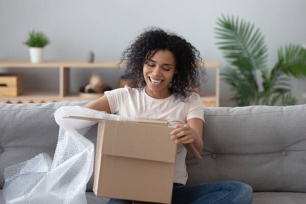 Smiling black girl unpack parcel at home shopping online