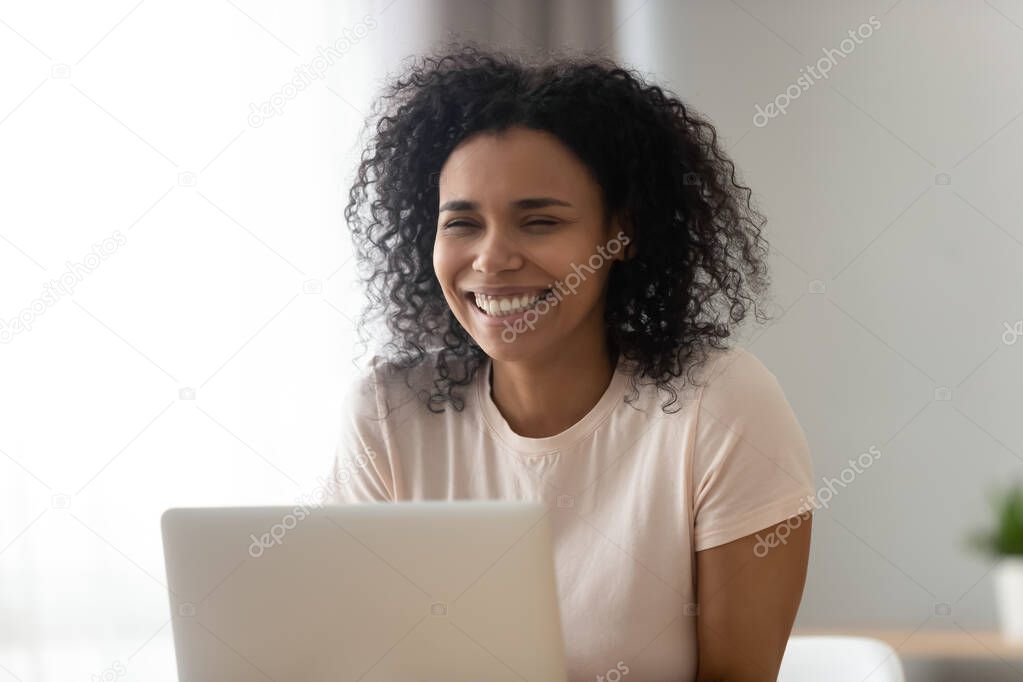 Smiling black girl laughing getting pleasant message on laptop