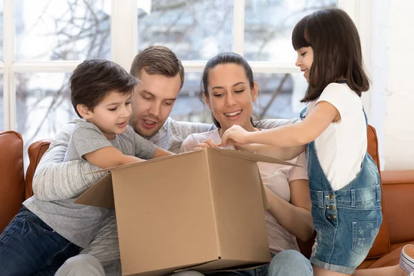 Büyük bir karton kutu taşıyan, teslimat paketini açan meraklı mutlu bir aile.. — Stok fotoğraf