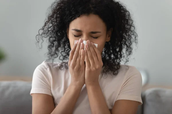 Kranke schwarze junge Frau mit Schnupfen bläst Nase — Stockfoto