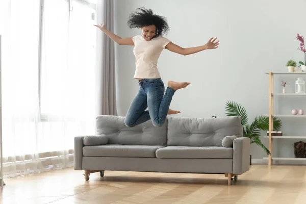 Opgewonden zwart vrouw veel plezier springen hoog thuis — Stockfoto