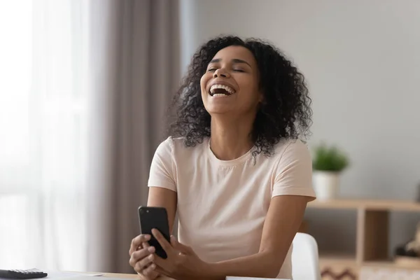 Sonriente chica negra riendo viendo divertido video en el teléfono celular — Foto de Stock