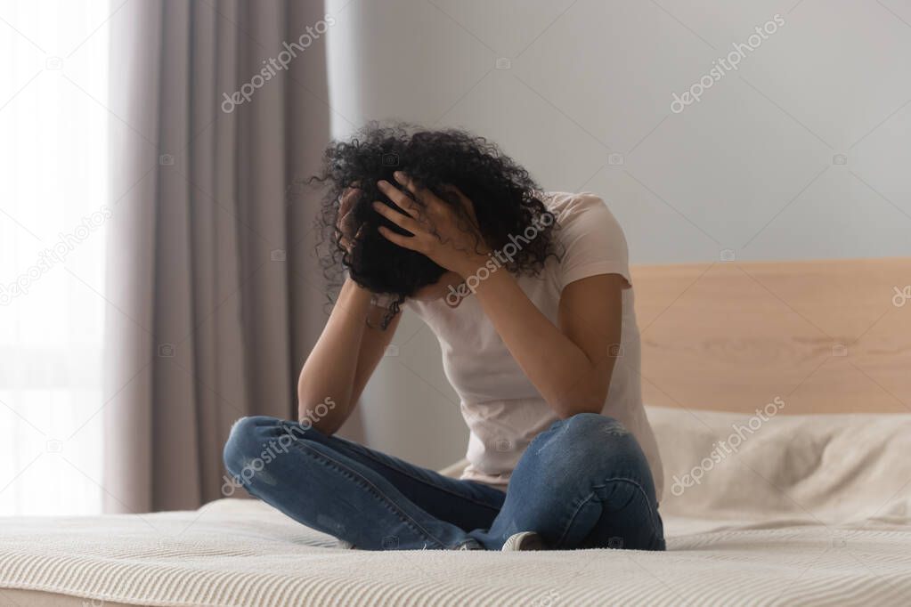 Depressed black girl sit on bed having life problems